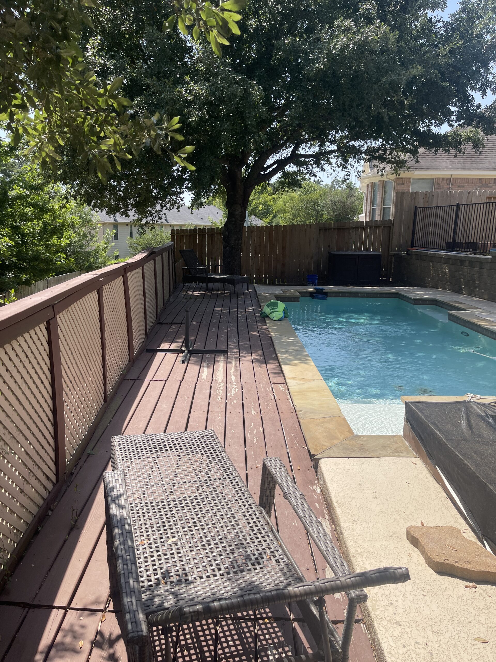 A deck with a pool and a tree.