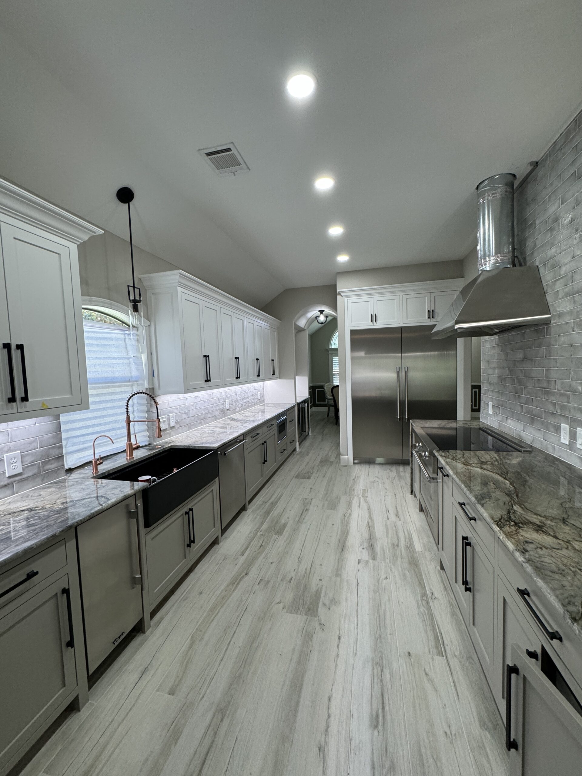 A kitchen with white cabinets and marble counter tops.