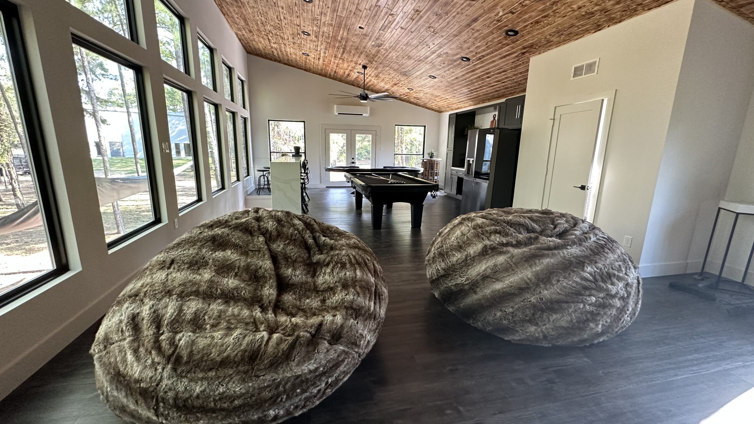 A pool table and two large round chairs.
