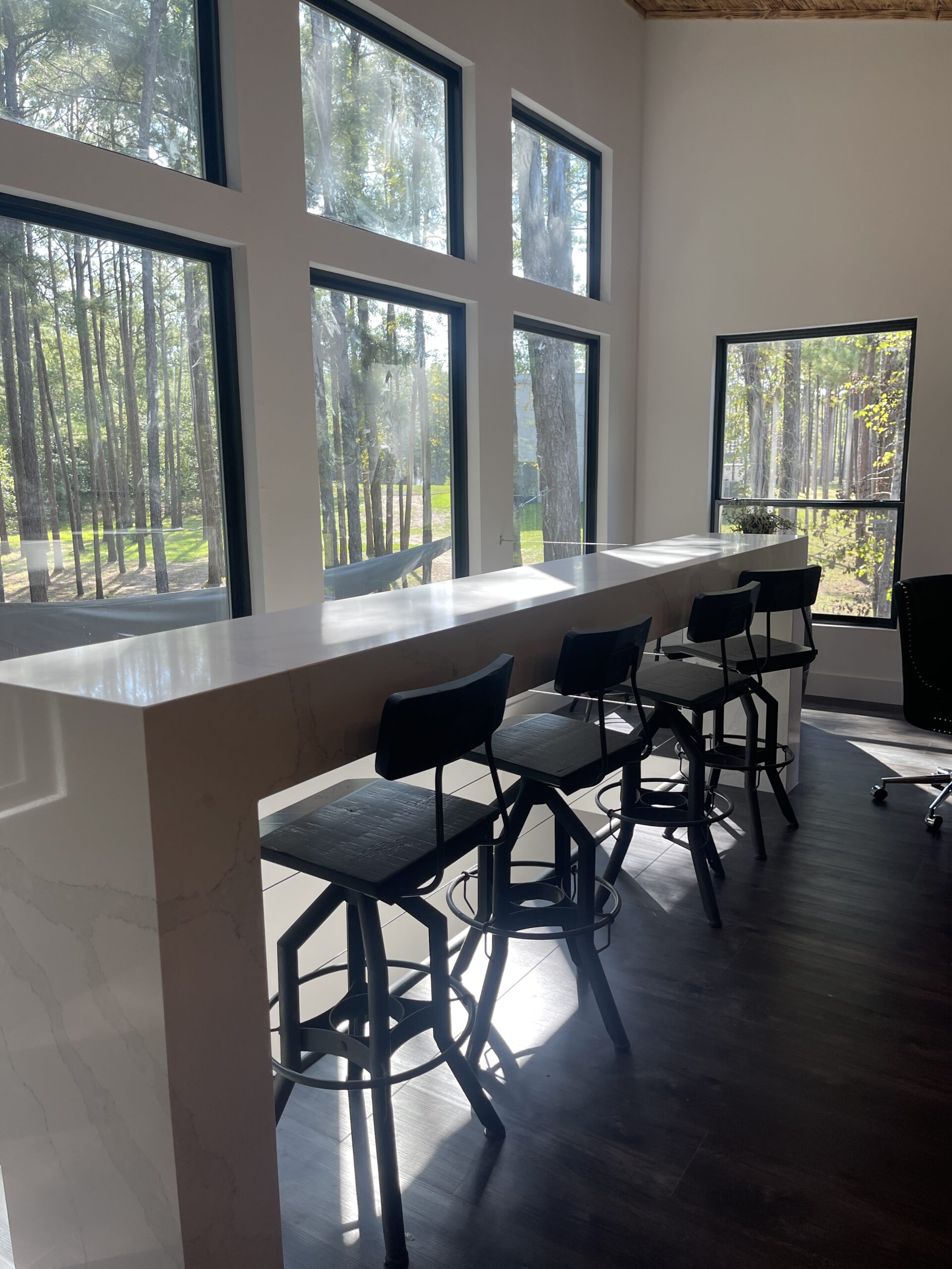 A room with a long counter and chairs.